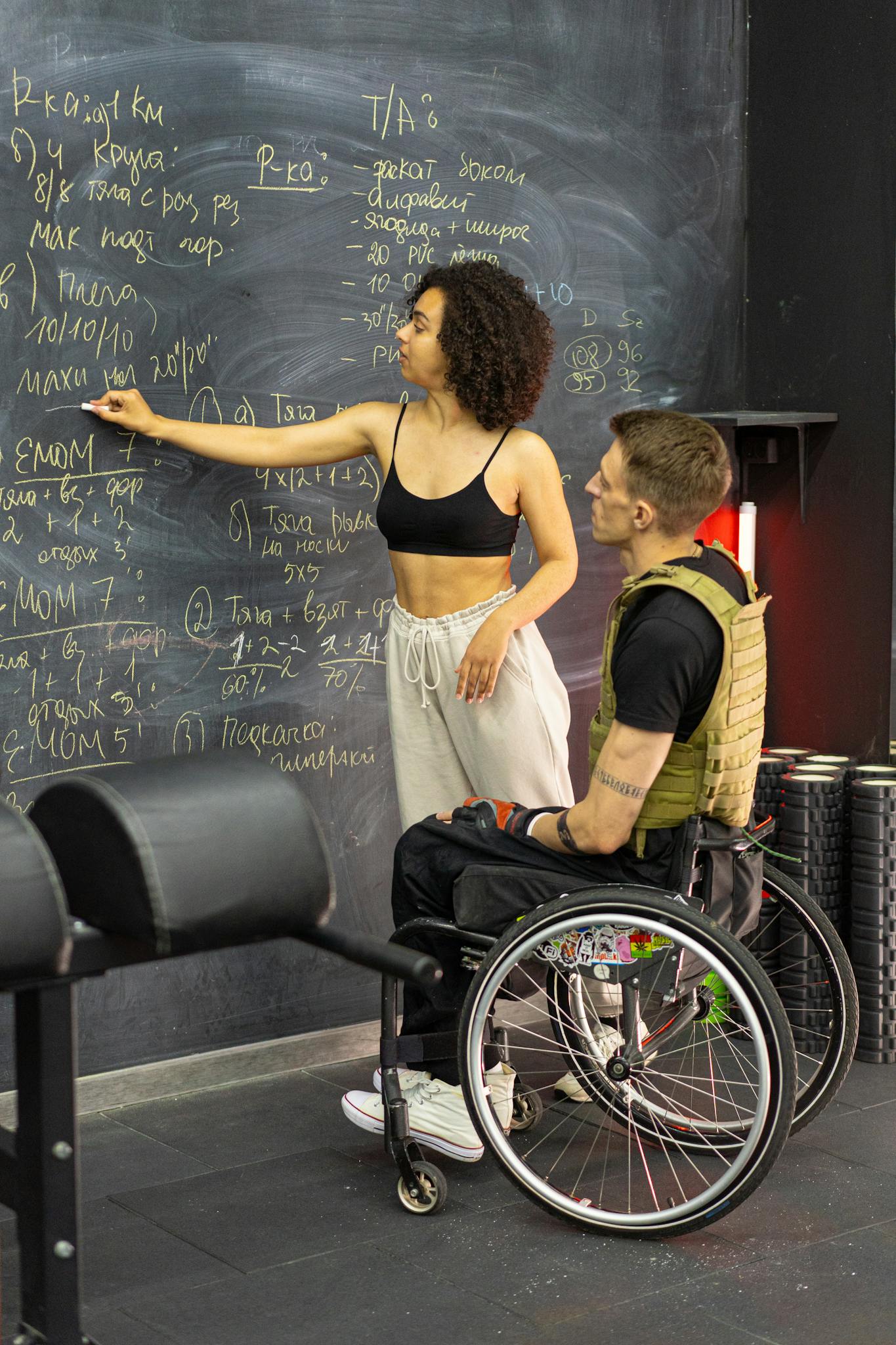 Two individuals engaged in learning with a blackboard, focusing on inclusive education and fitness.